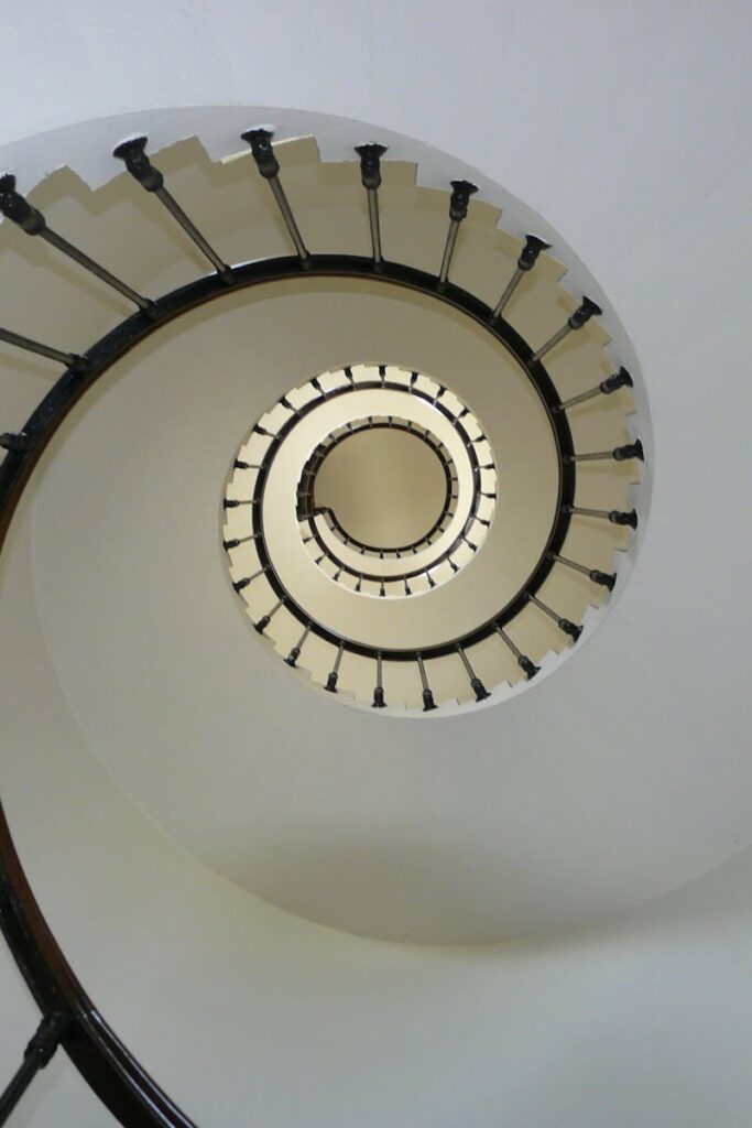 Elegant spiral staircase captured from above, showcasing architectural design and symmetry.