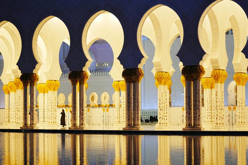 Stunning view of Sheikh Zayed Grand Mosque's arches at twilight with reflections in Abu Dhabi.