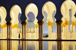 Stunning view of Sheikh Zayed Grand Mosque's arches at twilight with reflections in Abu Dhabi.
